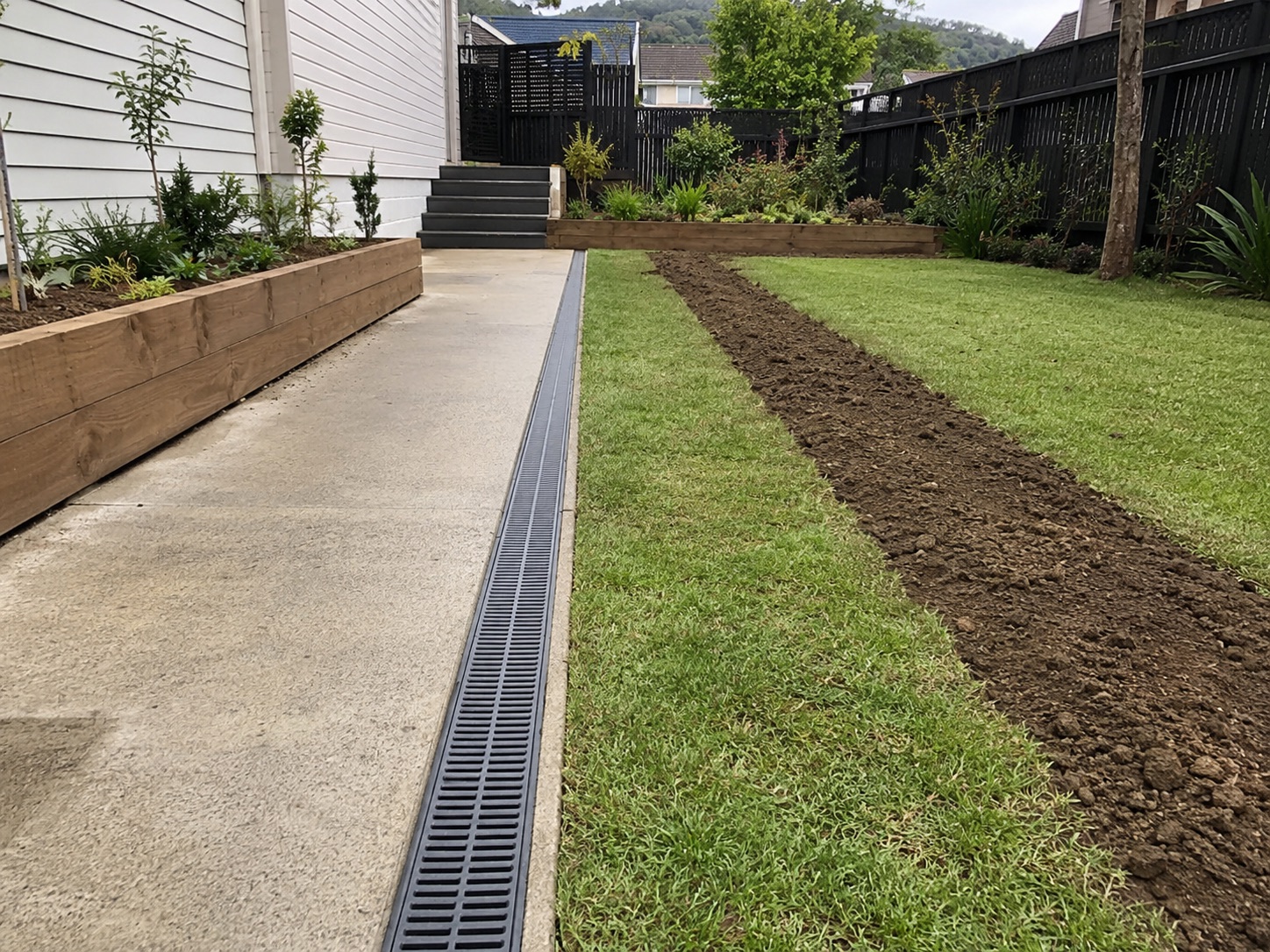 New channel drain beside a path with fresh drainage runs in the lawn