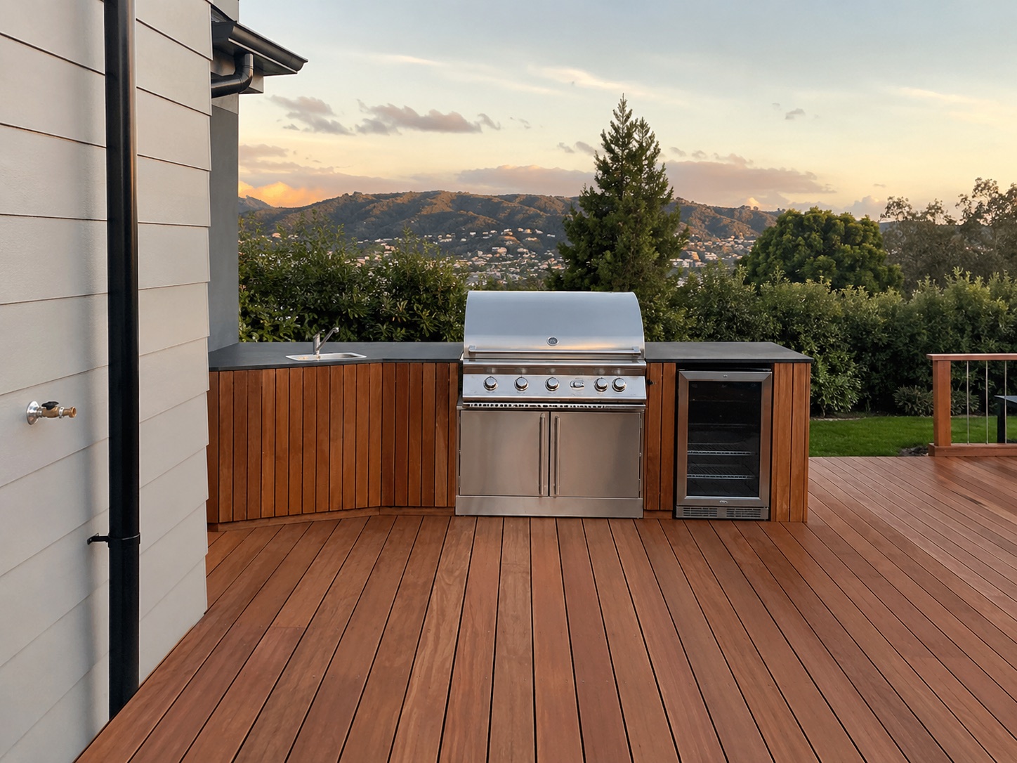 A finished outdoor kitchen with plumbed gas BBQ on a new timber deck at dusk